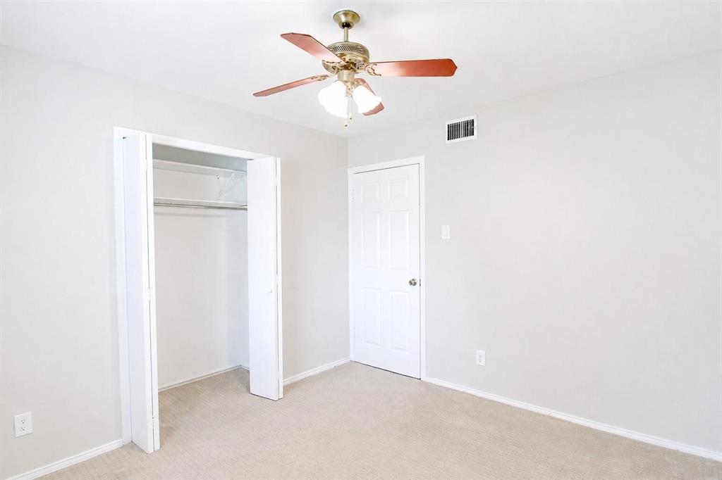 Neutral-toned interior featuring wall-to-wall carpeting, a six-panel interior door, a bi-fold closet door, and a ceiling fan with integrated light fixture