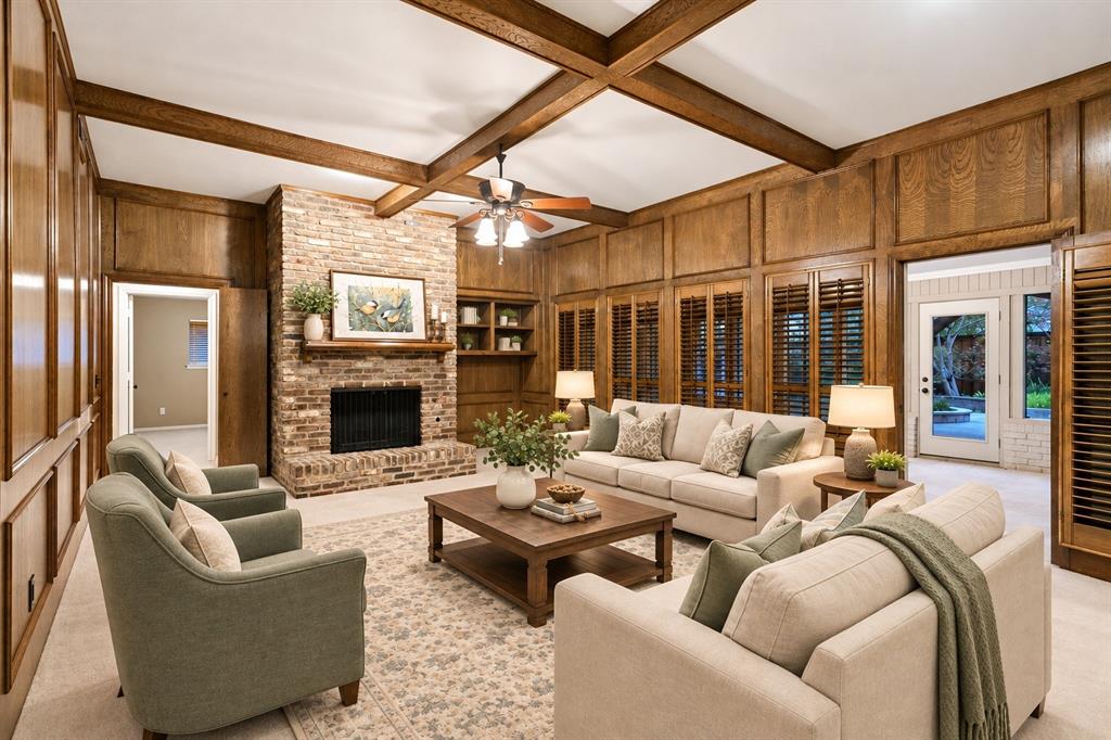 Gather here for great conversation and warmth in this great room w beamed ceiling and rich, warm paneling, gas FP and raised hearth -virtual staging