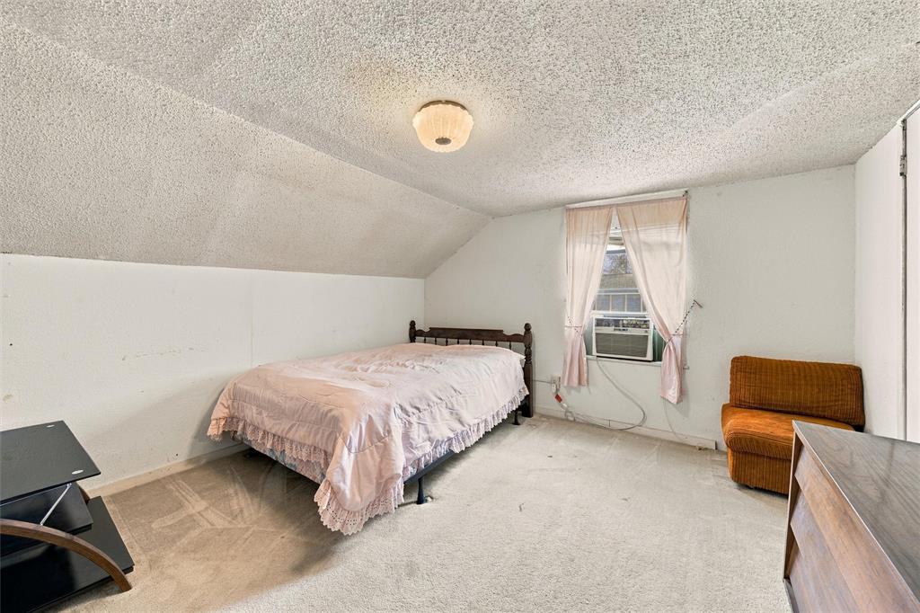 Sloped ceiling featuring a textured finish, neutral carpeting, and a central dome-style ceiling light