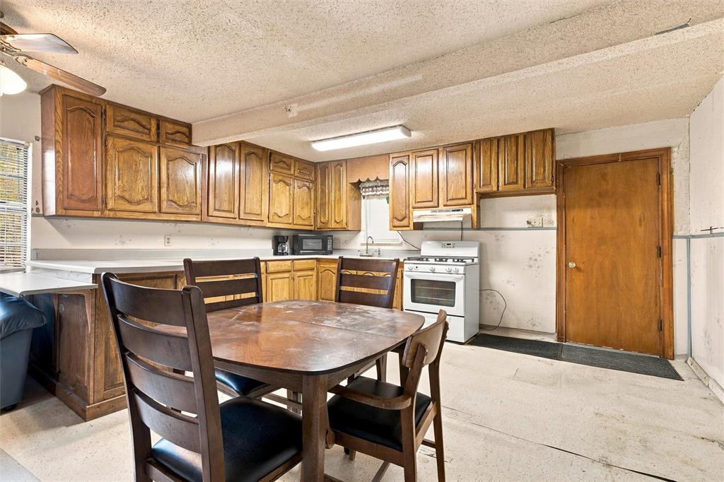 Kitchen featuring wood cabinetry, integrated countertops, ceiling-mounted lighting, and a four-burner gas range