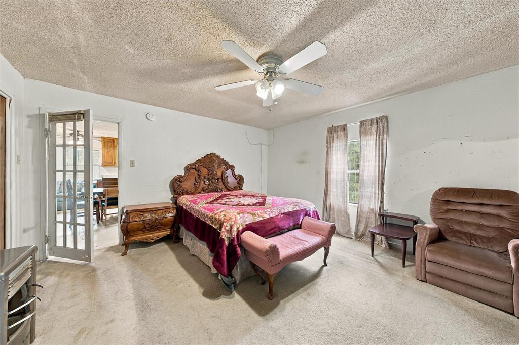 Interior space featuring a textured ceiling, neutral-tone carpeting, a white multi-panel door with glass inserts, and a central ceiling fan with integrated lighting