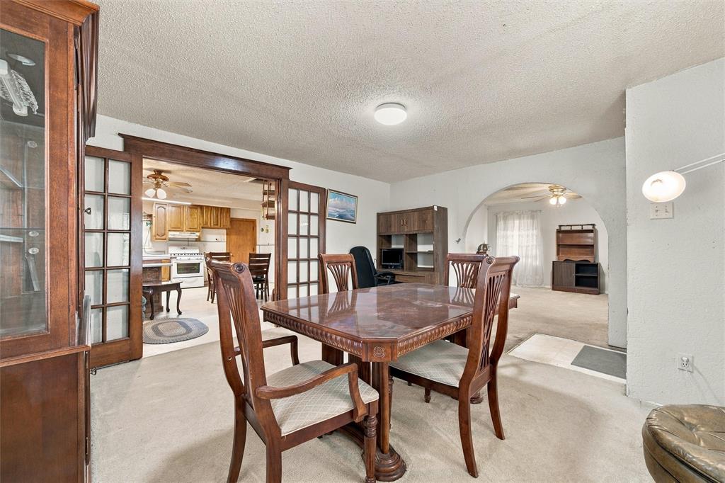 Room featuring dual glass-panel wood-frame doors, a prominent arched wall opening, and wall-mounted light fixture