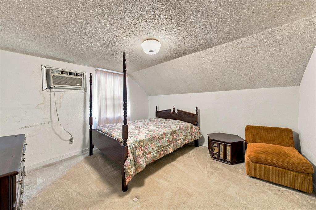 Interior room featuring sloped ceilings, wall-to-wall carpeting, and a built-in wall-mounted air conditioning unit