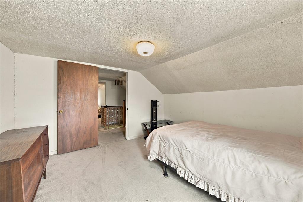 Interior room featuring a sloped ceiling, wall-to-wall carpeting, a solid wood door, and a flush-mount ceiling light fixture