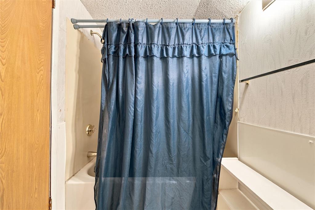 Bathtub enclosure featuring integrated wall panels, a metal showerhead, and a wall-mounted faucet fixture