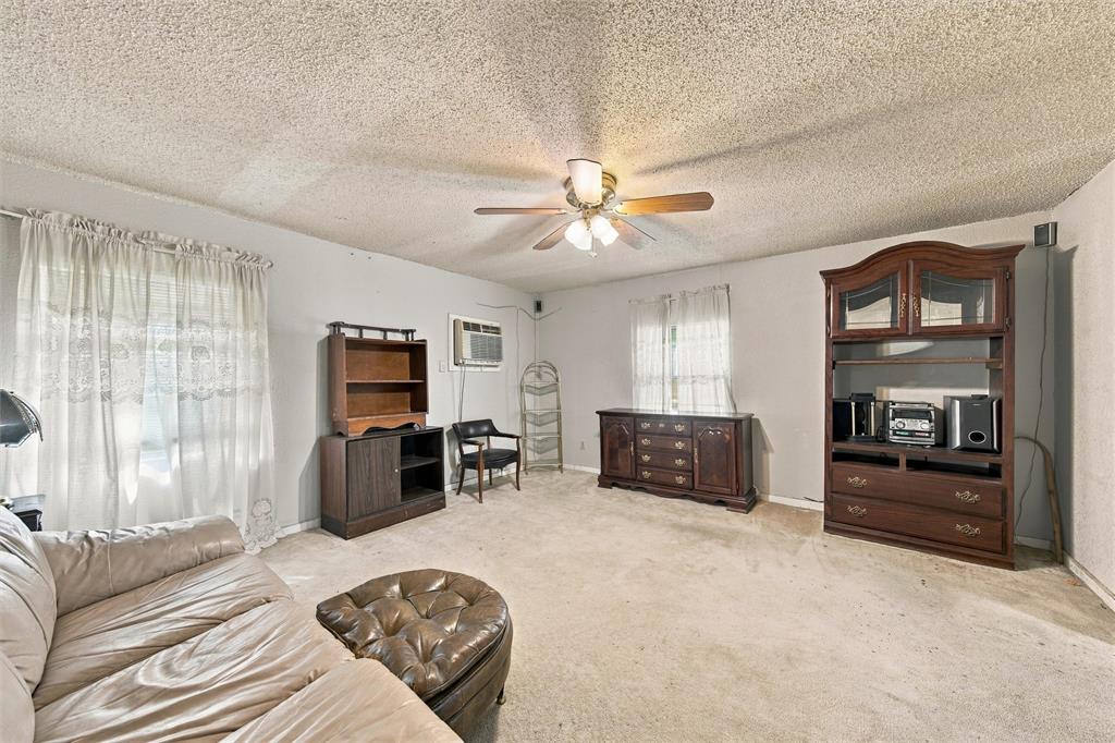 Living area featuring textured ceiling, carpeted flooring, and a ceiling-mounted light fixture with a fan