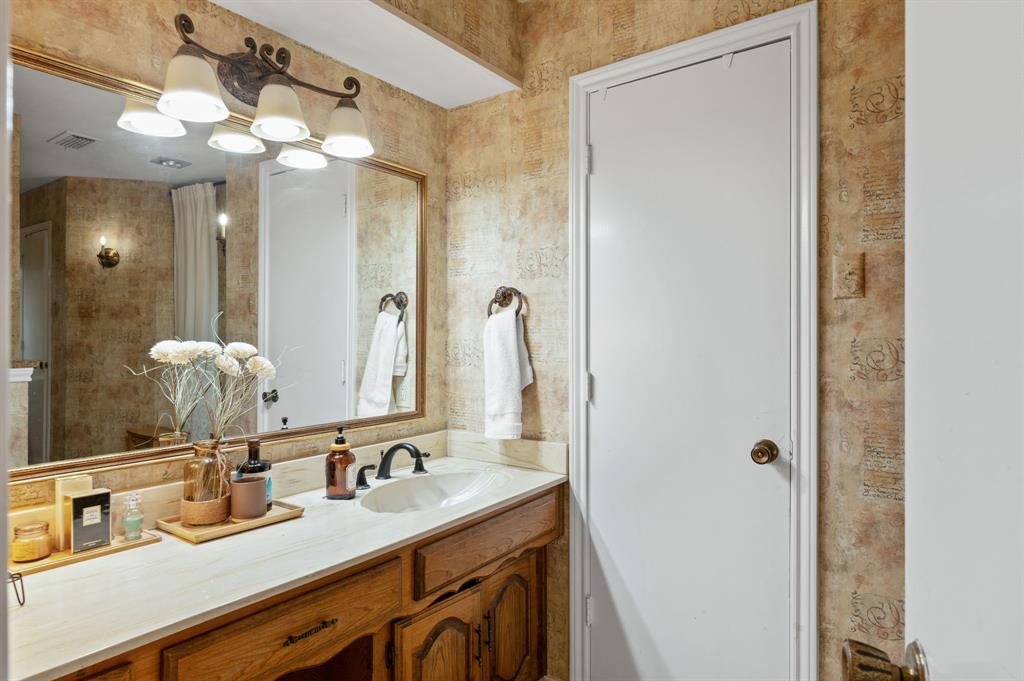 Bathroom vanity featuring a wood cabinet, light-toned countertop, oval undermount sink, and multi-light wall-mounted fixture above a framed mirror