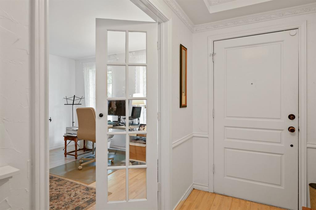 Entryway featuring a white paneled door, crown molding, chair rail trim, and a glass-paneled French door