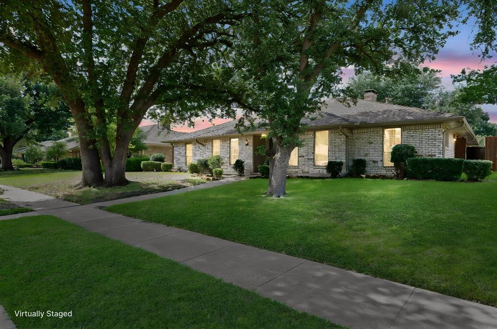 Single-story brick exterior featuring a hipped roof, mature shade trees, and a concrete walkway