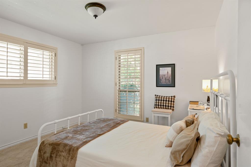Neutral wall finishes, carpeted flooring, and plantation shutters on both windows