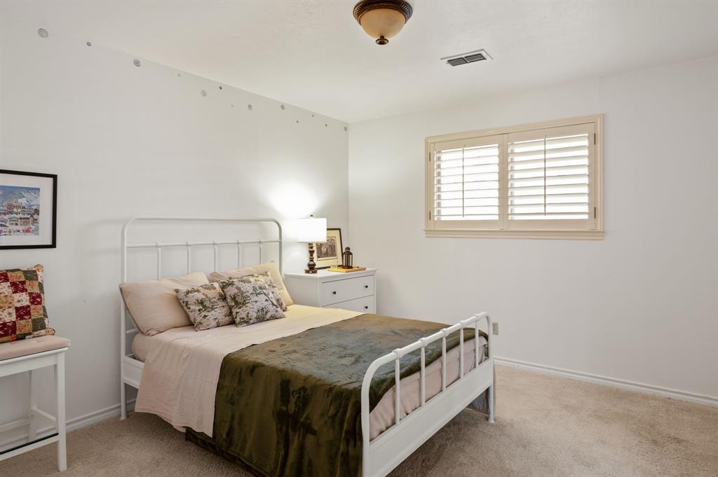 Neutral-toned interior space featuring light-colored wall-to-wall carpeting, white interior shutters, and a central ceiling-mounted light fixture