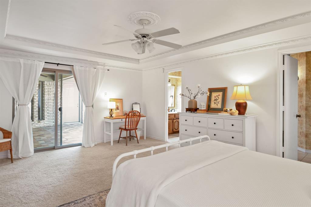 Tray ceiling with crown molding, ceiling fan with decorative medallion, and glass sliding door featuring exterior patio access