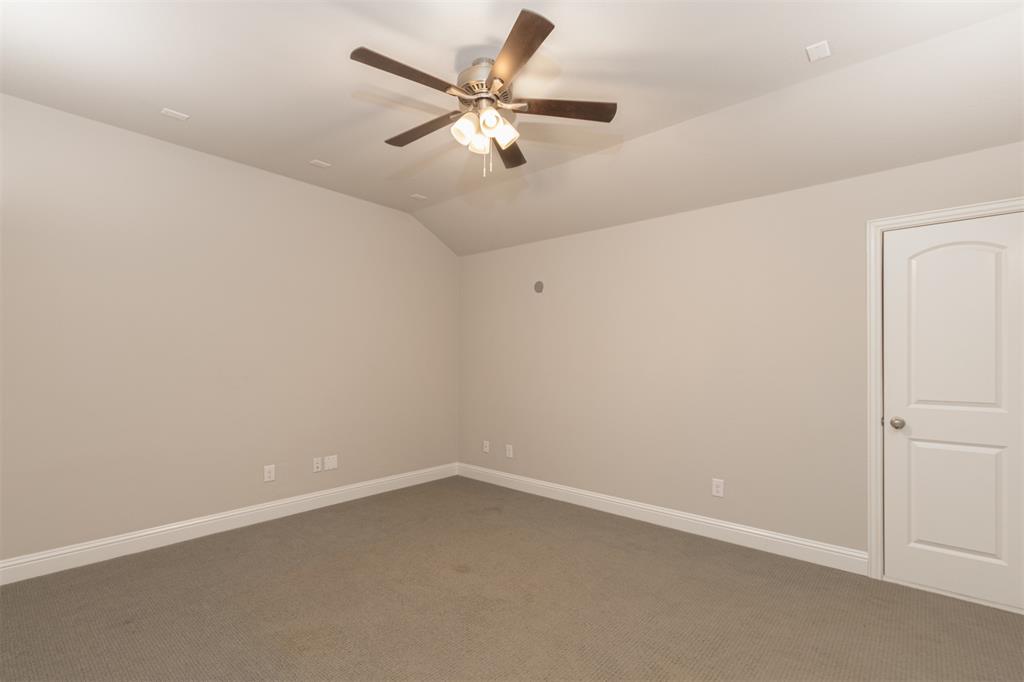 Neutral-toned interior featuring vaulted ceilings, wall-to-wall carpeting, and a multi-blade ceiling fan with integrated lighting