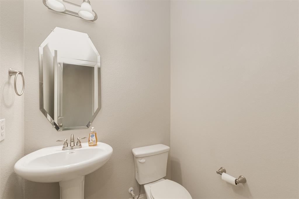 Pedestal sink featuring a polished chrome widespread faucet, octagonal wall-mounted mirror, and two-light vanity fixture