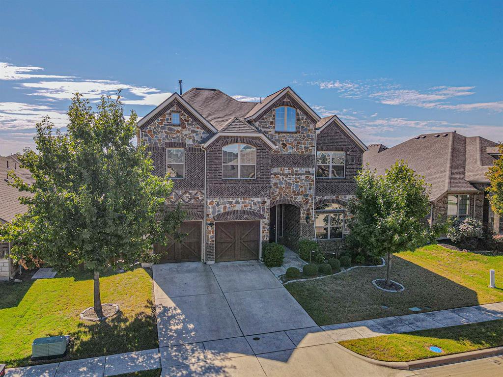 Multi-story exterior featuring a stone and brick facade, decorative cross-pattern brickwork, arched windows, and carriage-style garage doors