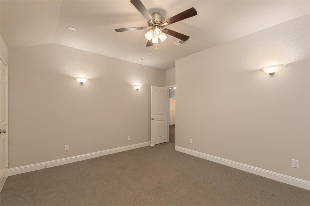 Vaulted ceiling, neutral wall tones, carpeted flooring, multi-light ceiling fan, and wall-mounted sconce lighting