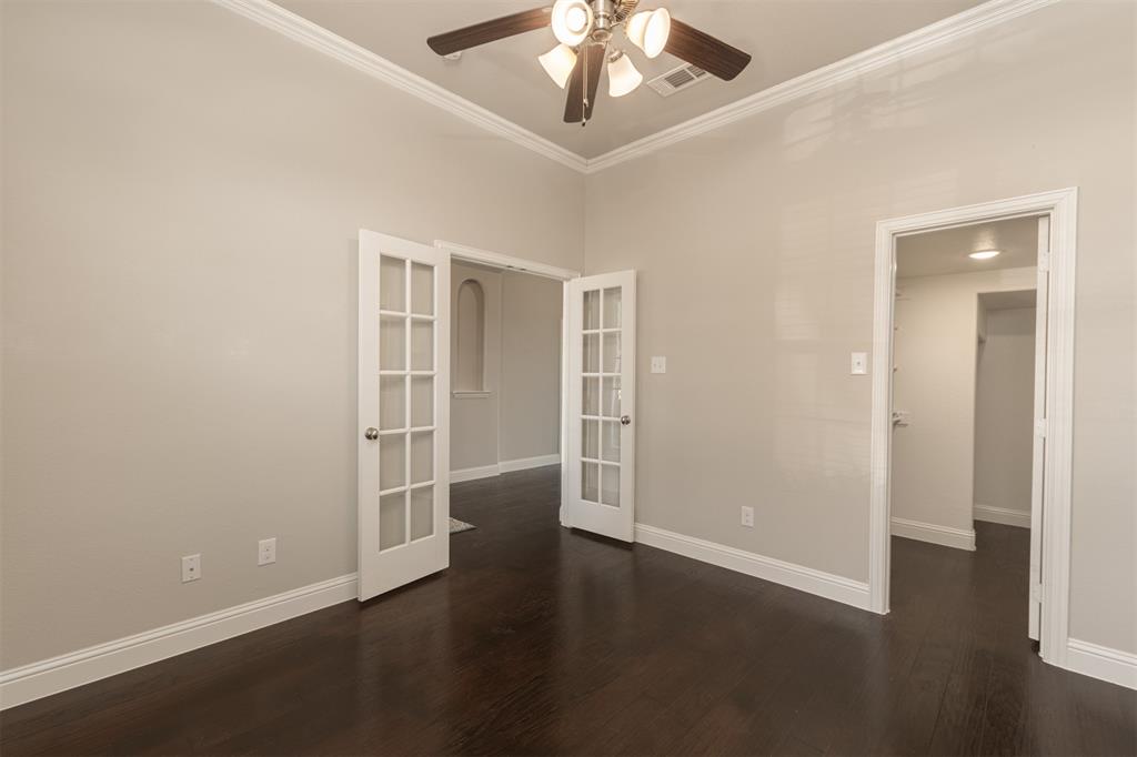 Room featuring wood-finish flooring, high ceilings with crown molding, double French doors, and a decorative arched wall niche
