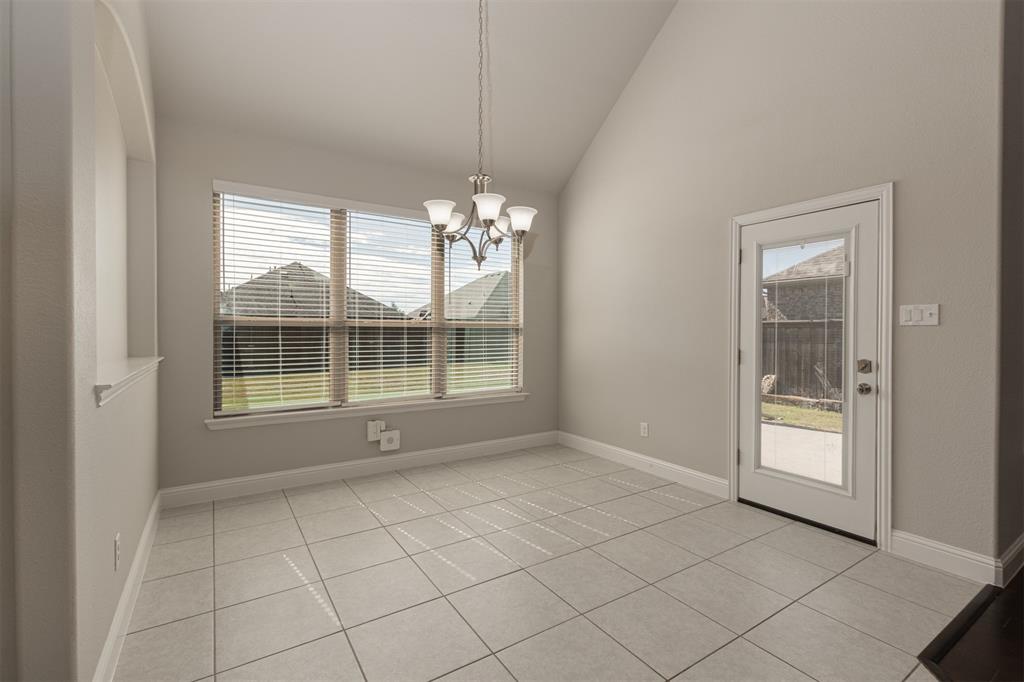 Vaulted ceilings, neutral tile flooring, multi-pane window with natural light, multi-light chandelier, and glass-paneled exterior door