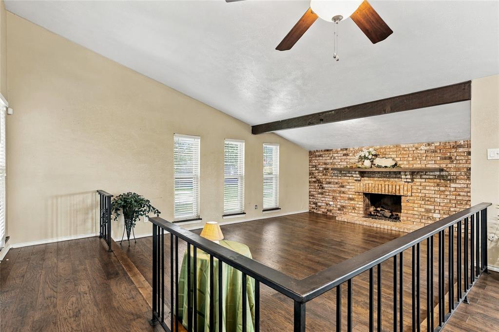 Wide-angle view of the living room showcasing the floor-to-ceiling brick fireplace, vaulted ceiling, and abundant natural light.