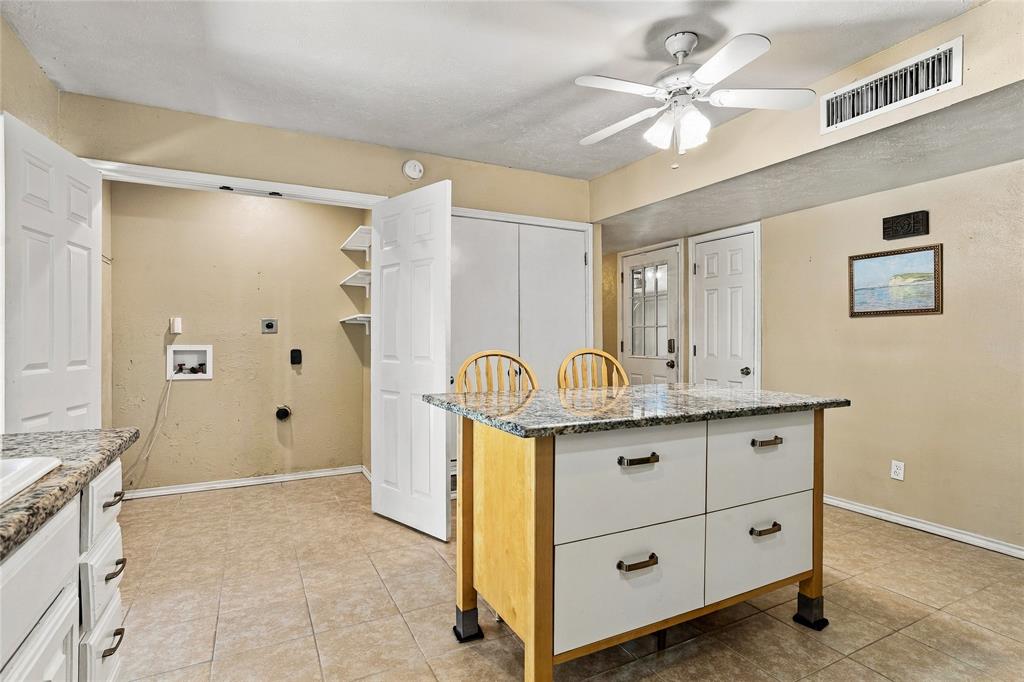 Spacious kitchen with white cabinetry, generous counter space, a center island, and a bright, functional layout.