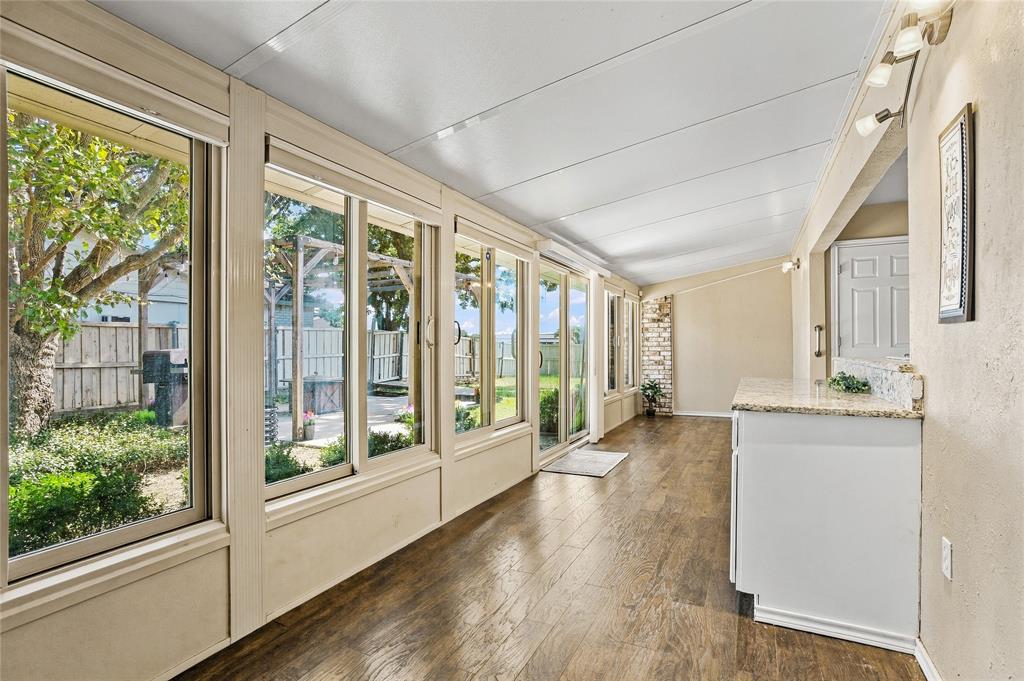 Bright sunroom featuring expansive windows, abundant natural light, and wood-look flooring—ideal for enjoying views of the backyard.