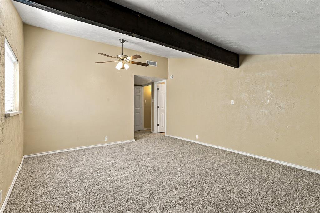 Generously sized bedroom with carpeted flooring, neutral finishes, a ceiling fan, and an open layout.