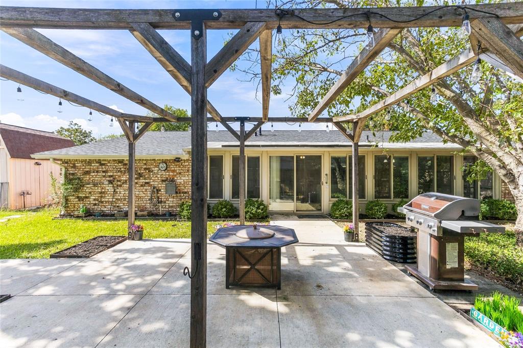 Covered outdoor entertaining area featuring a pergola-style roof structure, outdoor grill, and patio space overlooking the backyard.