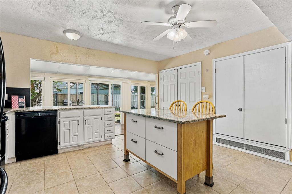 Alternate kitchen view highlighting the center island, contrasting black appliances, white cabinetry, and an open layout.