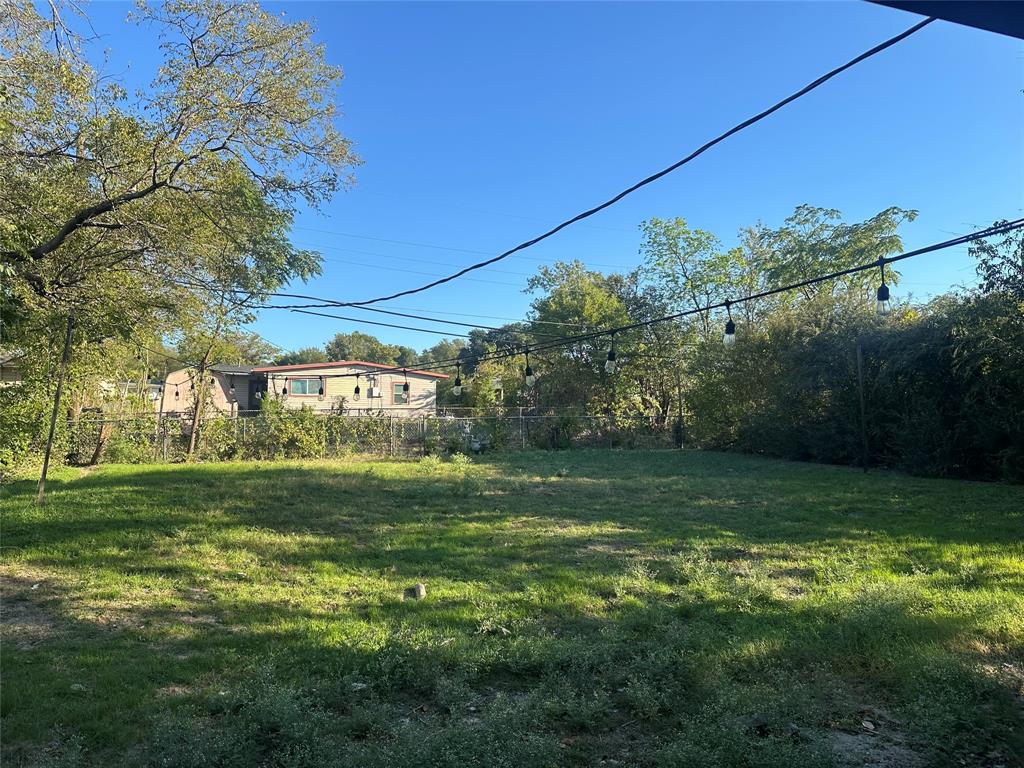 Expansive backyard featuring a fenced perimeter, mature trees, and overhead string lighting Expansive backyard featuring a fenced perimeter, mature trees, and overhead string lighting