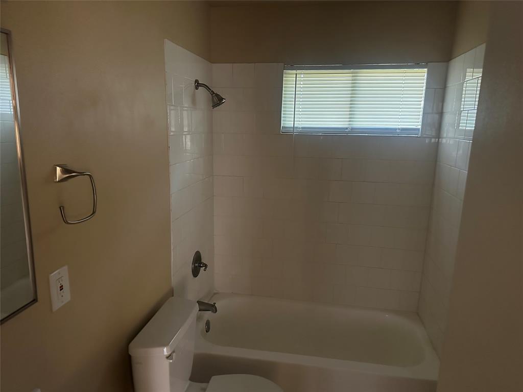 Tub and shower combination featuring white subway tile surround, polished metal fixtures, and a recessed window Tub and shower combination featuring white subway tile surround, polished metal fixtures, and a recessed window