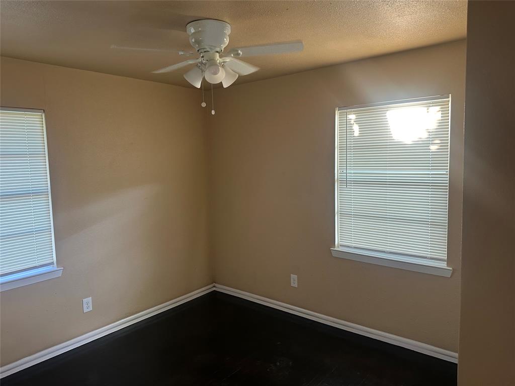 Dark-toned wood-finish flooring, white multi-light ceiling fan, and windows equipped with horizontal blinds Dark-toned wood-finish flooring, white multi-light ceiling fan, and windows equipped with horizontal blinds
