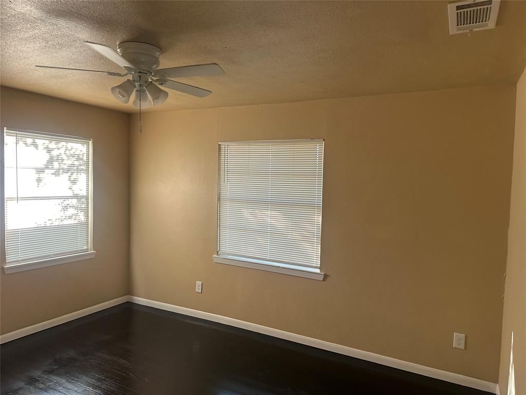 Room featuring wood-finish flooring, two windows with horizontal blinds, and a white ceiling fan with integrated lighting Room featuring wood-finish flooring, two windows with horizontal blinds, and a white ceiling fan with integrated lighting