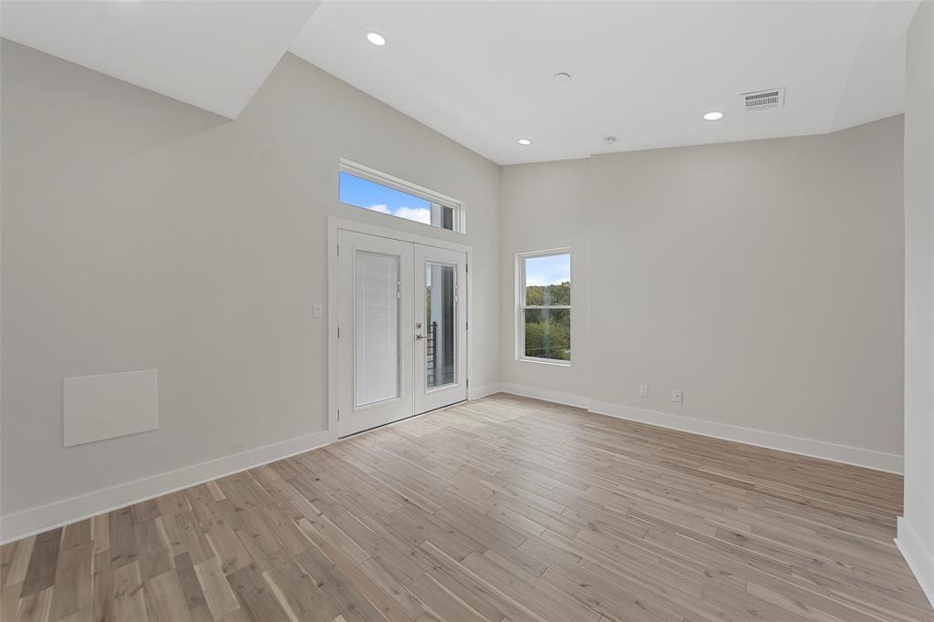 Vaulted ceiling with recessed lighting, wood-finish flooring, and double glass-paned doors featuring a transom window