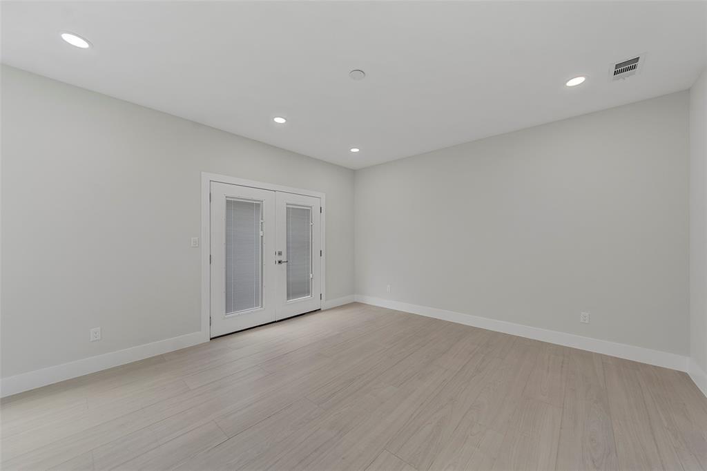 Neutral-toned room featuring wood-finish flooring, recessed lighting, and double glass-paneled doors