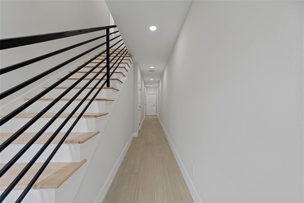 Staircase featuring wood-finish treads and a matte black horizontal railing, wood-finish flooring, and recessed ceiling lighting Staircase featuring wood-finish treads and a matte black horizontal railing, wood-finish flooring, and recessed ceiling lighting