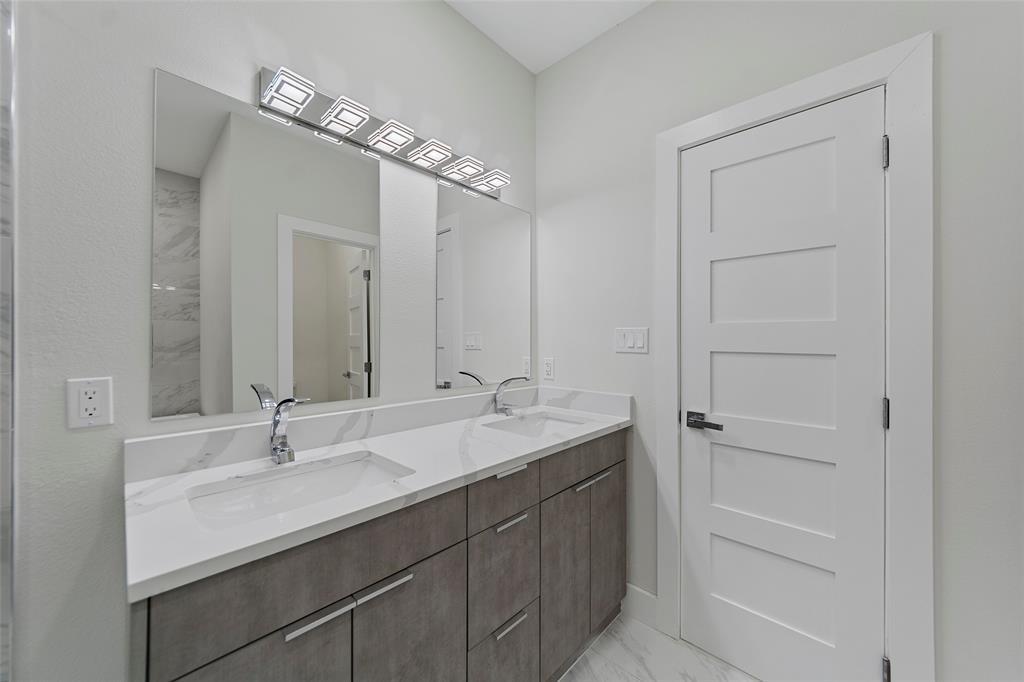 Dual vanity featuring a white countertop with integrated sinks, chrome fixtures, flat-panel cabinetry, a full-width mirror, and multi-light LED vanity lighting