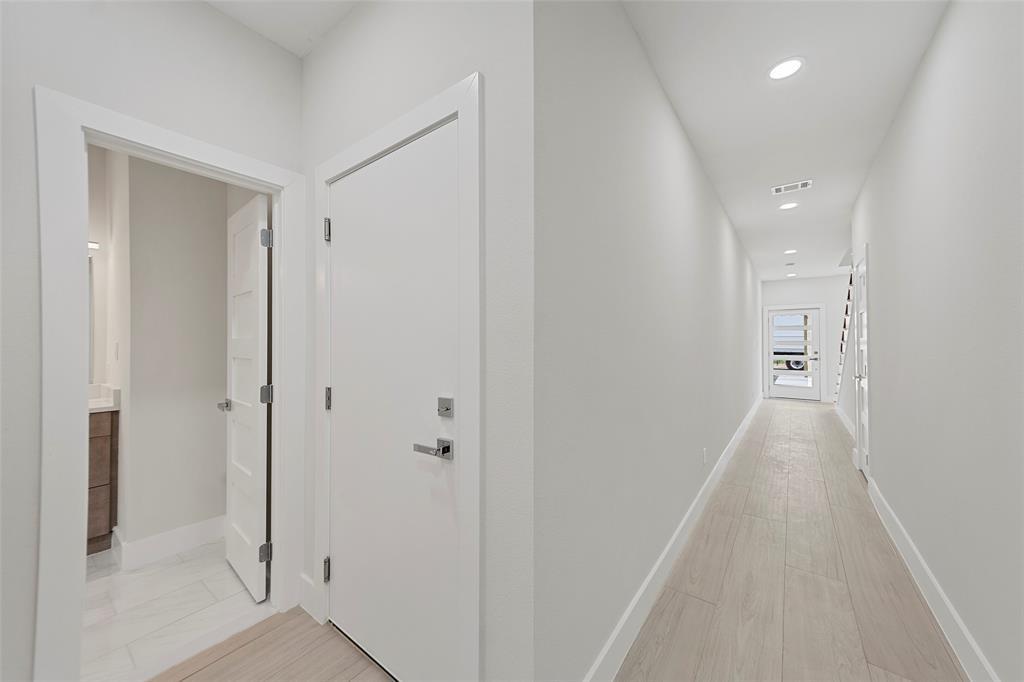 Neutral-toned interior hallway featuring wood-finish flooring, recessed lighting, and a multi-lite exterior entry door with a frosted glass panel Neutral-toned interior hallway featuring wood-finish flooring, recessed lighting, and a multi-lite exterior entry door with a frosted glass panel