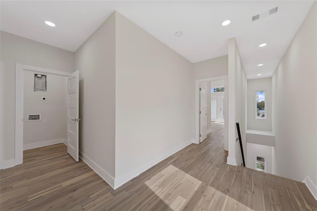 Neutral-toned interior featuring wood-finish flooring, recessed lighting, four-panel interior doors, and a staircase with a minimalist black handrail
