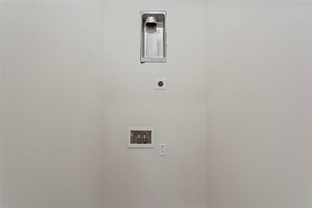 Dedicated laundry alcove featuring a recessed dryer vent, plumbing connections for a washing machine, and integrated electrical outlets