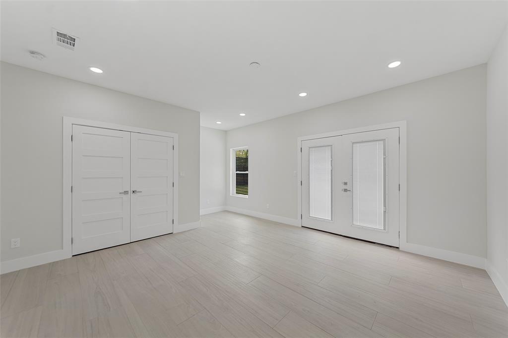 Neutral-toned interior featuring wood-finish flooring, recessed lighting, double-door closet with shaker-style panels, and glass-paneled double doors