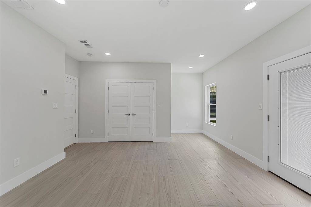 Neutral-toned interior space featuring wood-finish flooring, recessed lighting, double-panel interior doors, and a glass-paneled exterior door