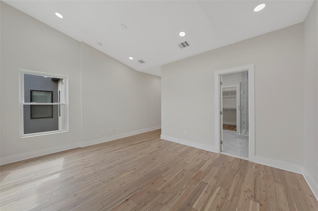 Vaulted ceiling with recessed lighting and wood-finish flooring