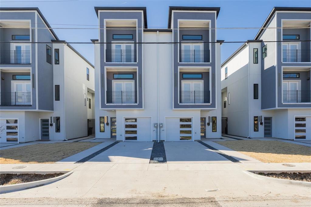 Contemporary multi-story exterior featuring a smooth stucco facade, dual-level balconies with metal railings, and attached garages with horizontal glass-paneled doors