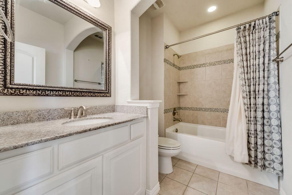 Full bathroom featuring shower / bath combo, tile patterned flooring, toilet, and vanity