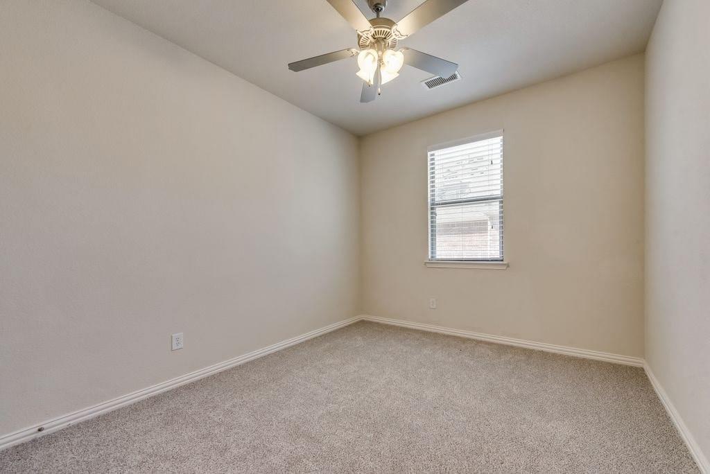 Carpeted empty room featuring ceiling fan