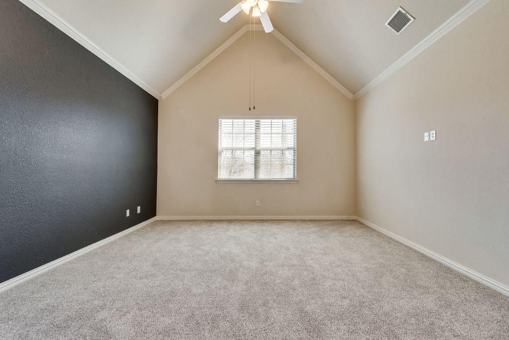 Unfurnished room with ceiling fan, light colored carpet, crown molding, and vaulted ceiling