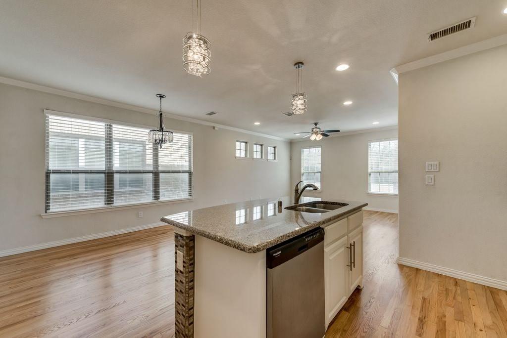 Kitchen featuring ceiling fan with notable chandelier, white cabinetry, light hardwood / wood-style flooring, a center island with sink, and stainless steel dishwasher