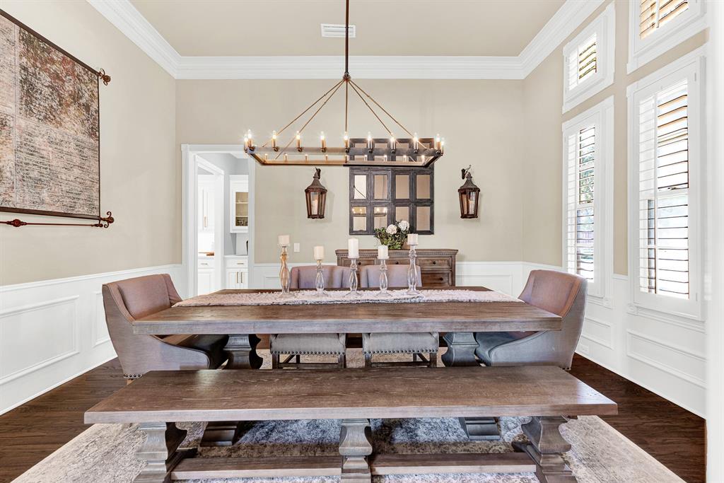 Refined wainscoting and classical crown molding wrap the perimeter, balancing structured design with ambient overhead glow. Picture gathering your favorite people around the table for an intimate dinner party that lingers long into the evening.