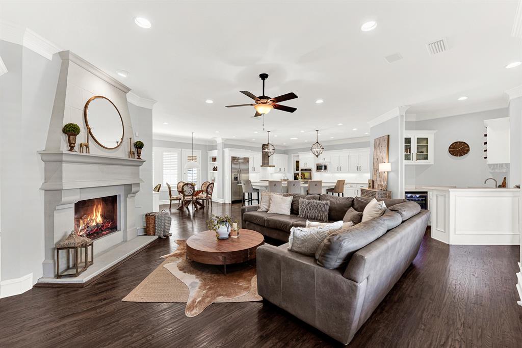 Recessed ceiling lighting and continuous dark hardwood floors create a vast, seamless flow connecting the living space, kitchen, and bar area. Picture throwing open the patio doors for effortless indoor-outdoor entertaining on warm summer evenings.