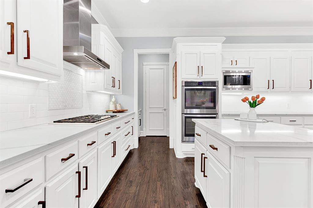 Built-in double ovens and deep storage drawers align along immaculate tiled backsplashes for sleek functionality. Picture baking holiday treats together as delicious scents fill every corner of your bright, airy home.